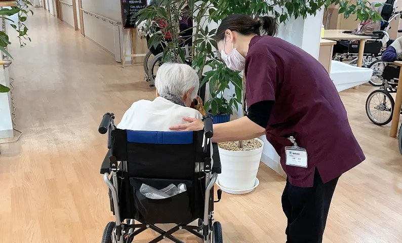 車椅子の入居者を見守るスタッフ