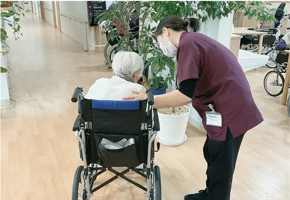 車椅子の入居者を見守るスタッフ